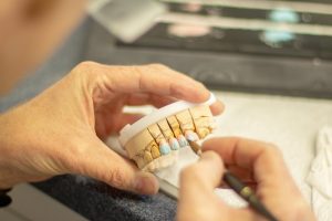 Technician hand-painting shade details onto a dental restoration model