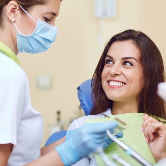 Smiling woman in the dental chair beside her dentist